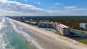 A coastal hotel with multiple buildings, a beach, and a view of the ocean.