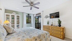 Ein Schlafzimmer mit Bett, Deckenventilator, Fernseher, Schrank und Fenster.
