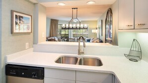 A modern kitchen with a built-in dishwasher, a stainless steel sink, and a pendant light fixture. - $150 activities - E-gift card when you book - Lakefront Screened in Porch | KLC 112 (Myrtle Beach)