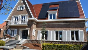 A two-story house with a brick facade, white shutters, and a red roof. - Amylia (De Haan)