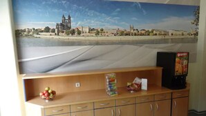 A room with a wooden cabinet, a television, and a poster of a cityscape. - Sleep & Go Hotel Magdeburg (Magdeburg)