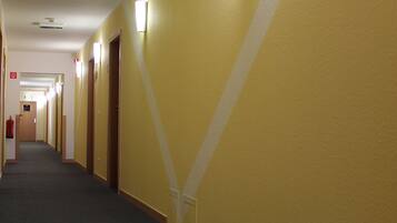 A long, narrow hallway with yellow walls and a dark carpet.