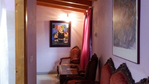 A room with a wooden ceiling, a sofa with patterned cushions, a dining table with chairs, and a framed picture on the wall. - CasaCándana (La Vecilla)