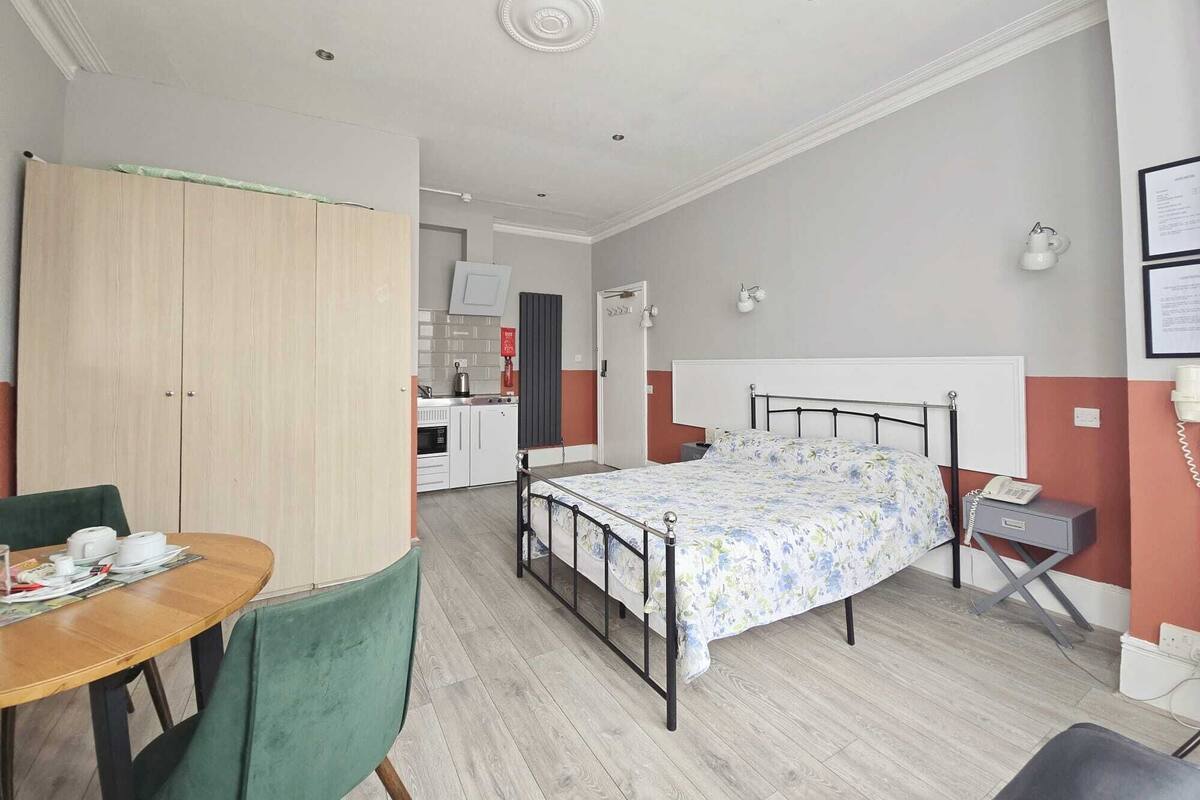 A compact room with a bed, a small table, and a chair.
