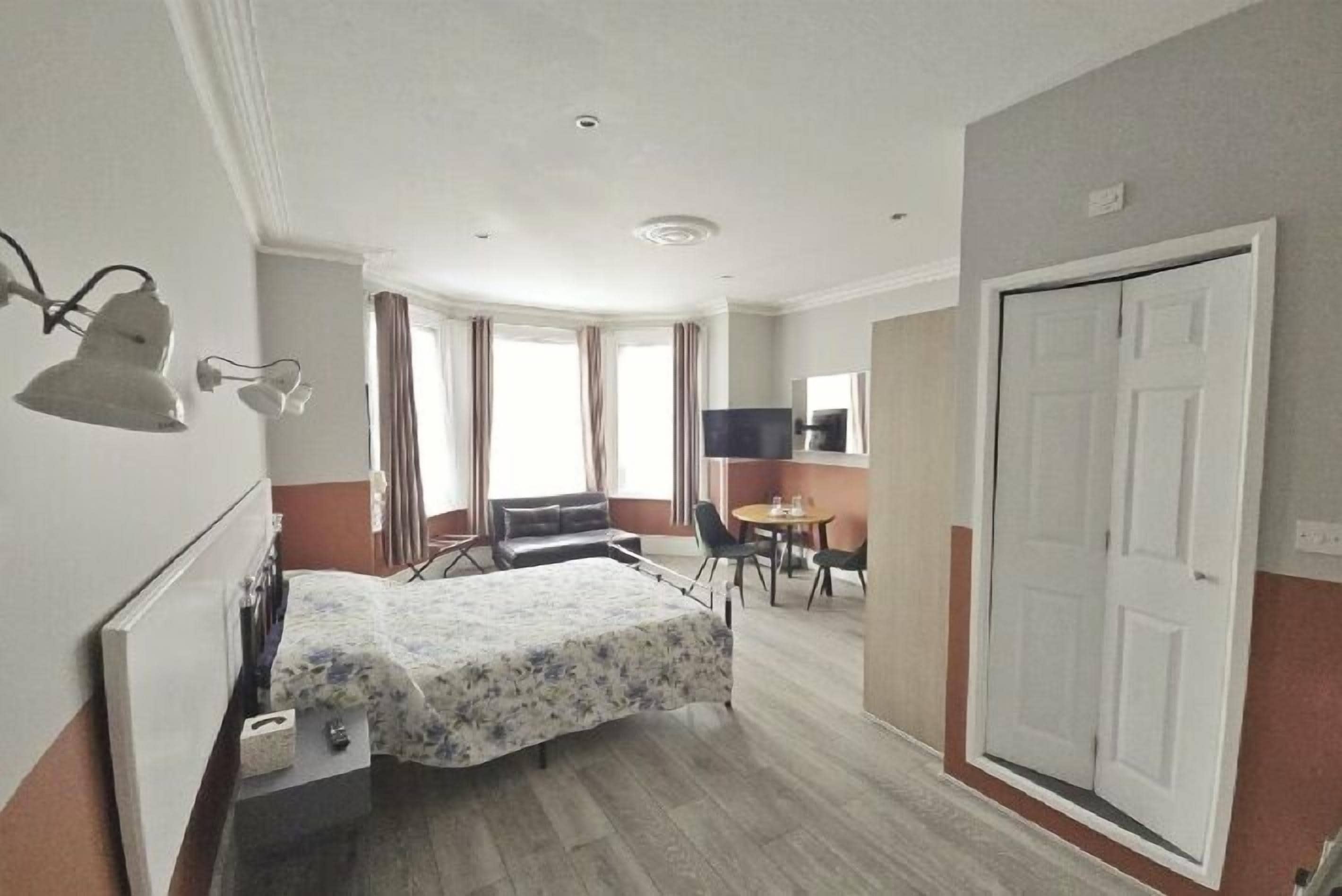 Una habitación de hotel con cama, escritorio, silla, televisor y puerta.