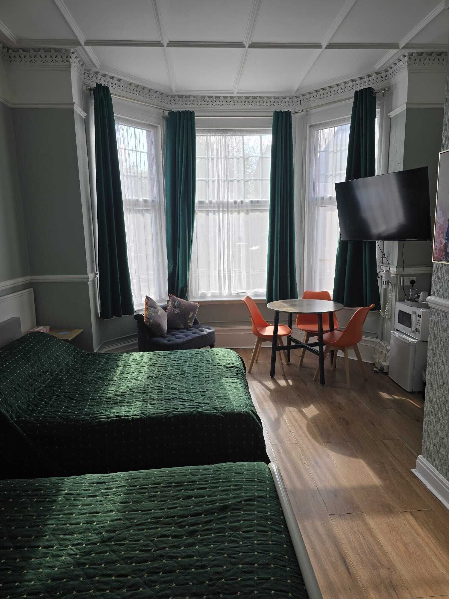 Une chambre avec deux lits, une table à manger avec des chaises, un téléviseur et un coin cuisine.