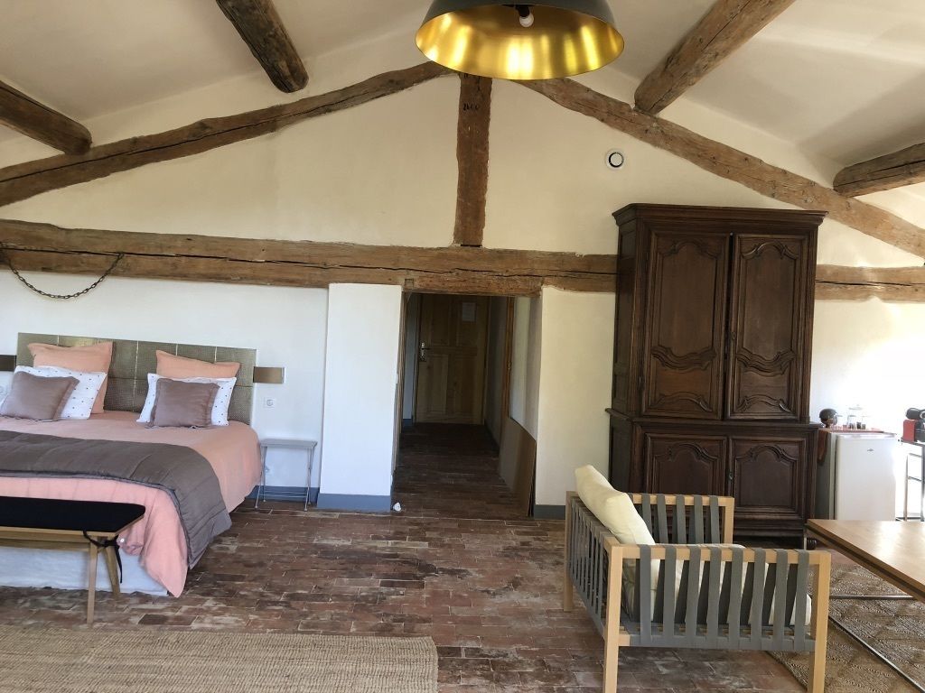 Un dormitorio con cama, vigas de madera, un armario y una silla.