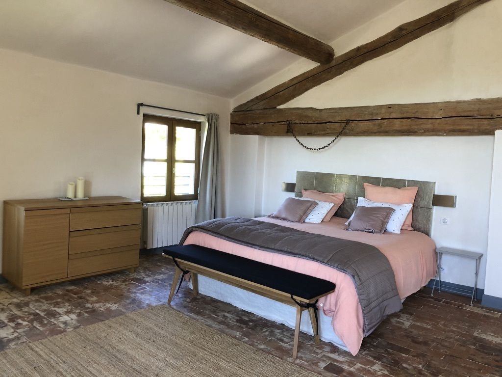 Une chambre à coucher avec un lit, un banc, une commode et une fenêtre.