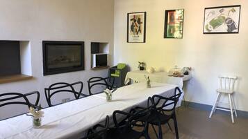 Un espace repas avec une longue table, des chaises noires et des œuvres d’art encadrées accrochées aux murs.