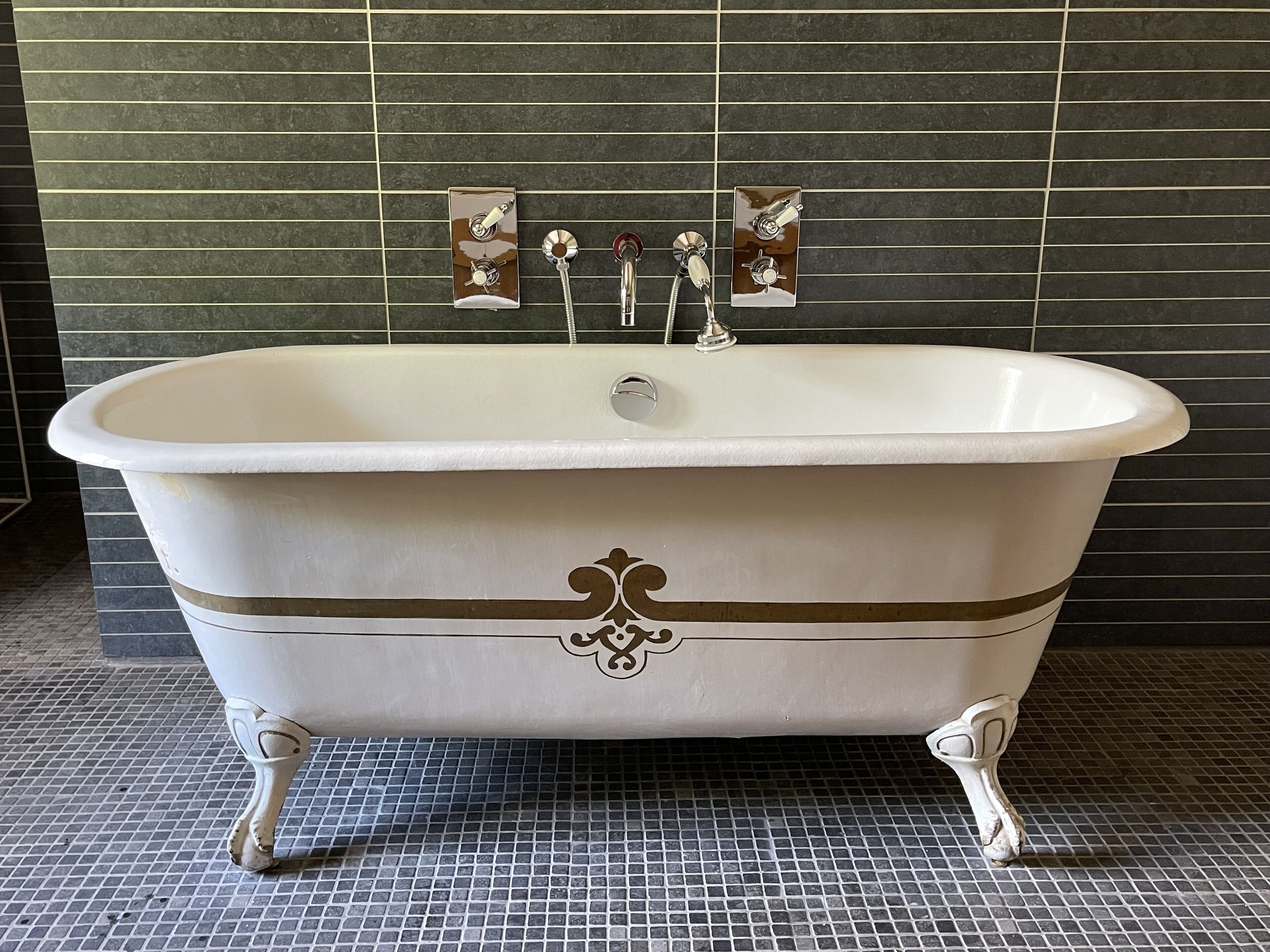 A freestanding bathtub with claw feet, a single faucet, and a decorative emblem on the front.