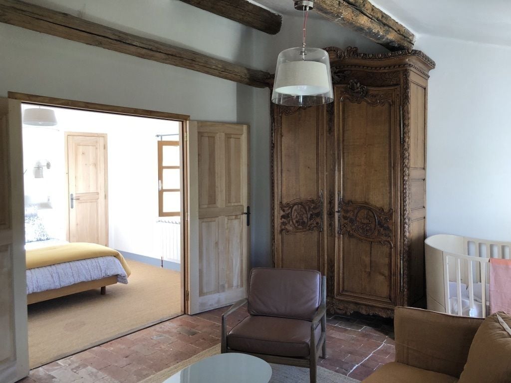 Une pièce comprenant un lit, une armoire en bois, un fauteuil en cuir et une table.