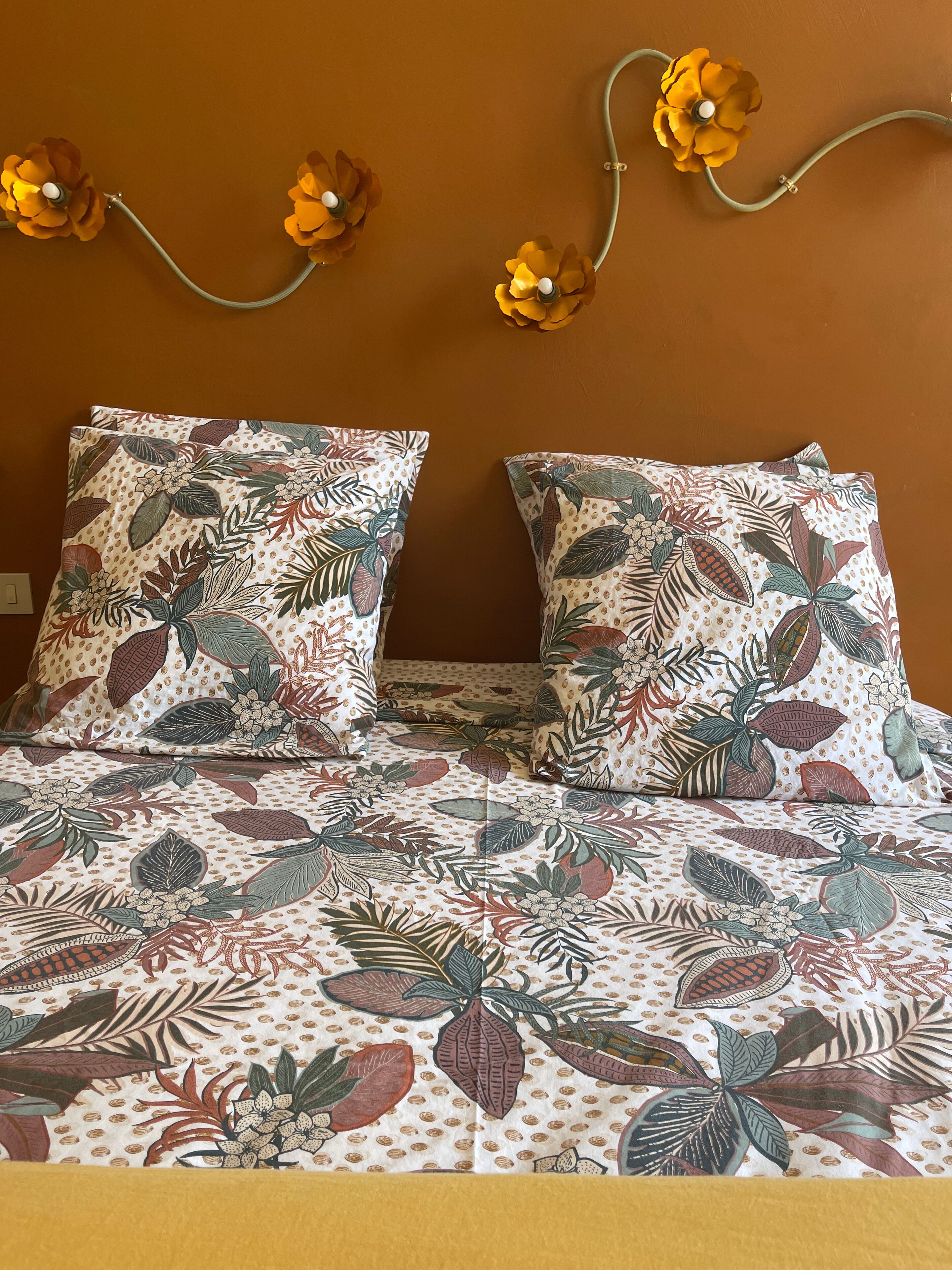A bed with floral-patterned bedding and decorative wall flowers.