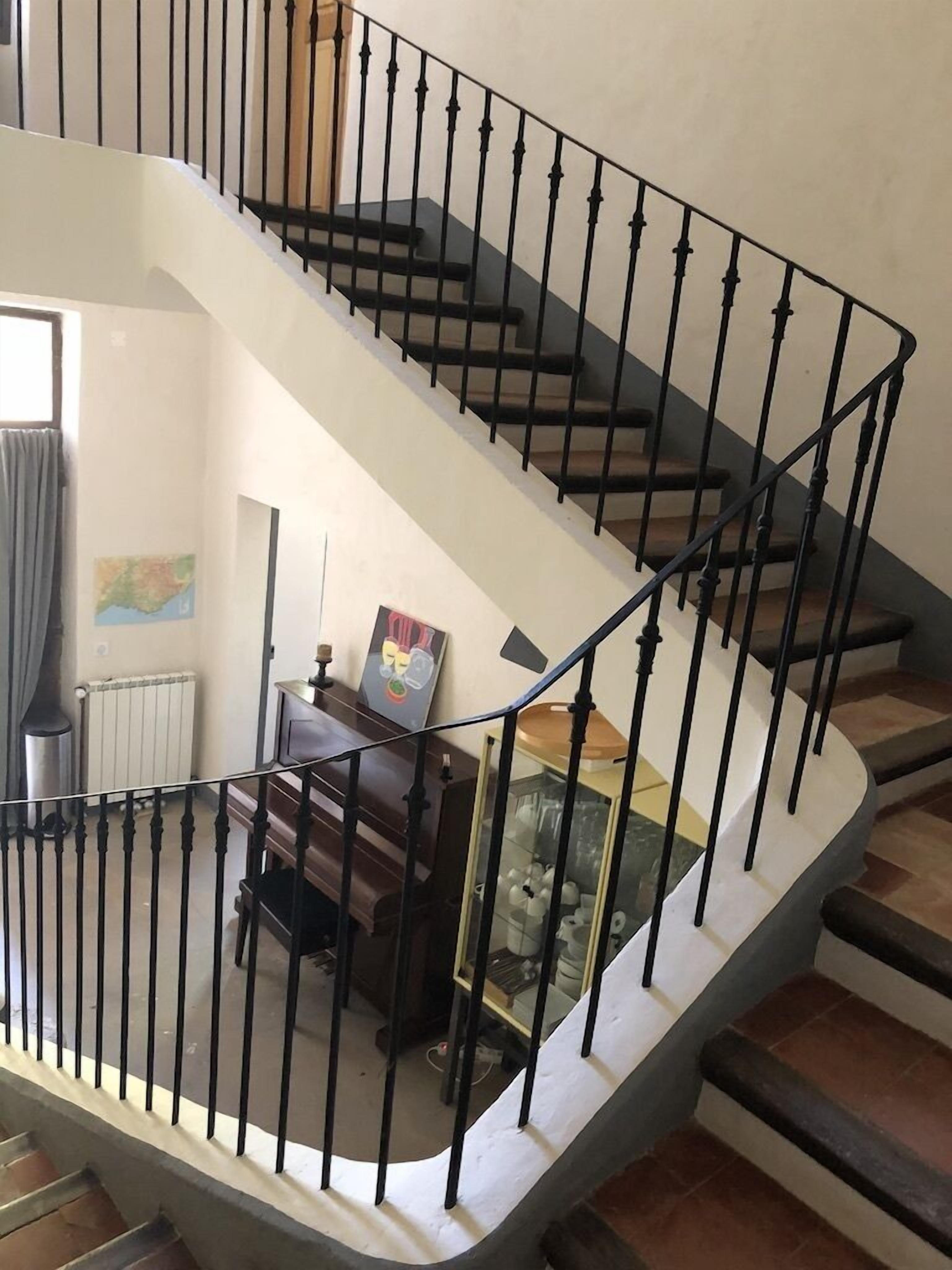 Eine Wendeltreppe mit schwarzen Geländern und Holzstufen, die zu einer oberen Etage führt.