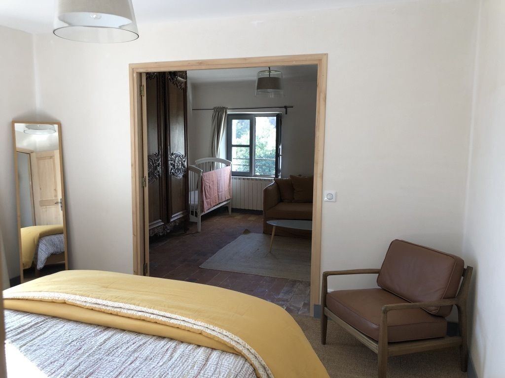 A bedroom with a bed, a chair, a mirror, and a window.