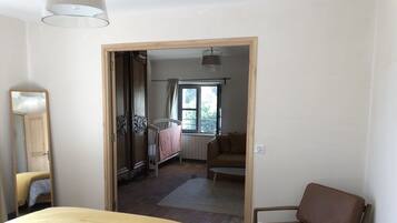 A bedroom with a bed, a chair, a mirror, and a window.