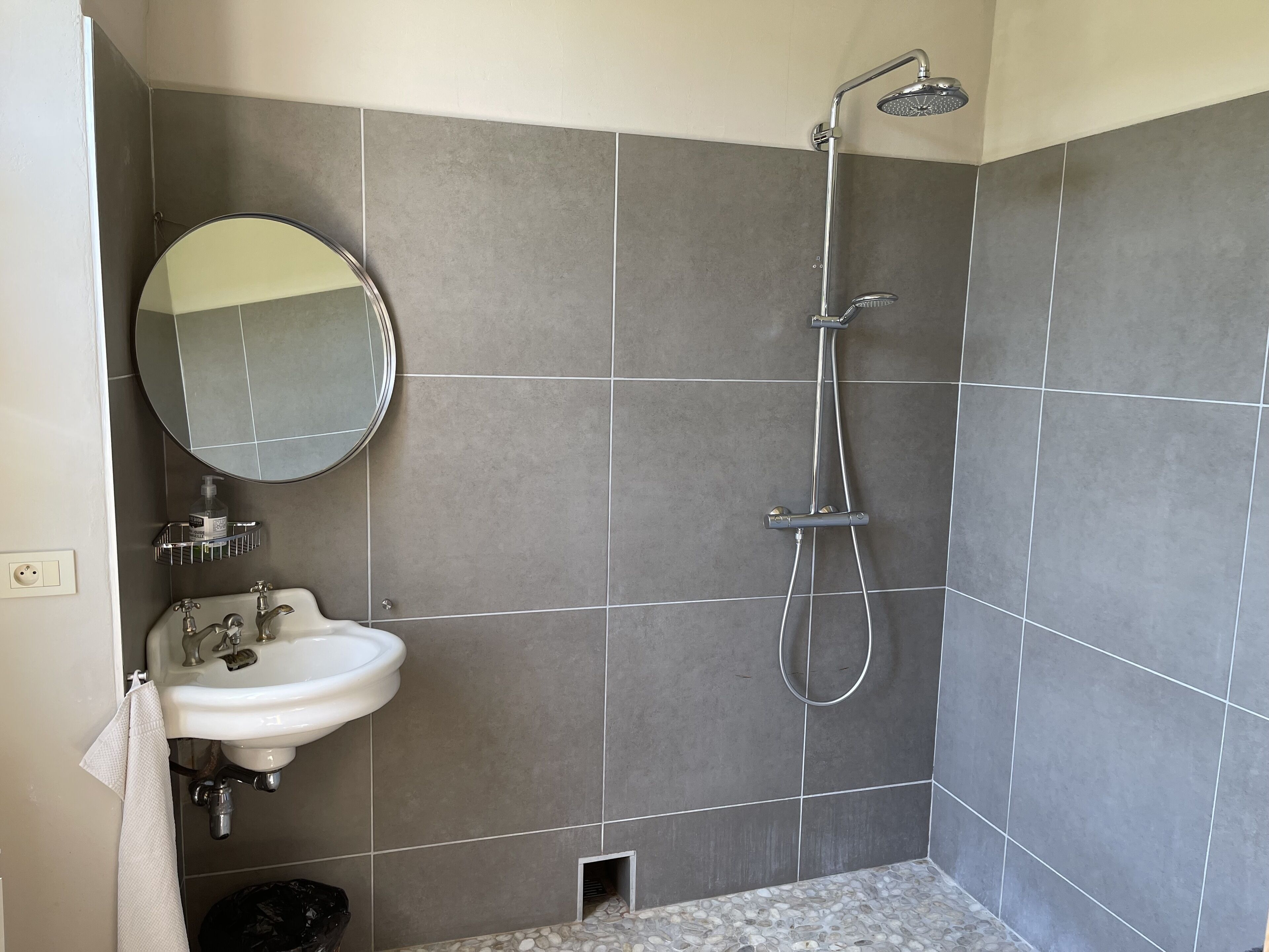 Baño con lavamanos, espejo y ducha.