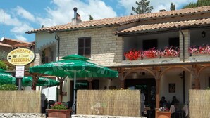 A traditional building with a tiled roof and a sign indicating a restaurant and pizzeria. - Affittacamere Villa Bagno Santo (Manciano)