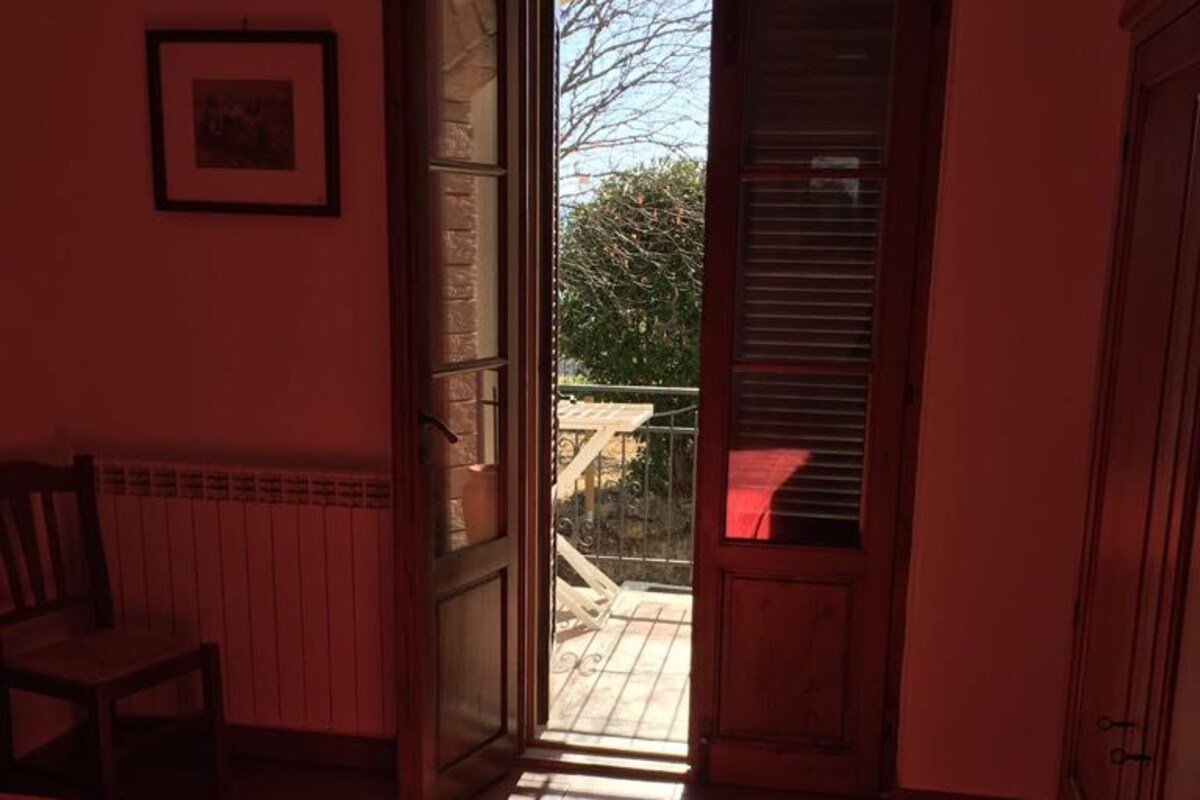 Et soveværelse med en seng, en stol, en radiator og en dør til en balkon.