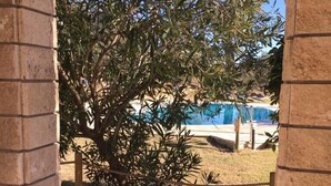 A view through a brick archway with a tree and a swimming pool in the background. - Affittacamere Villa Bagno Santo (Manciano)