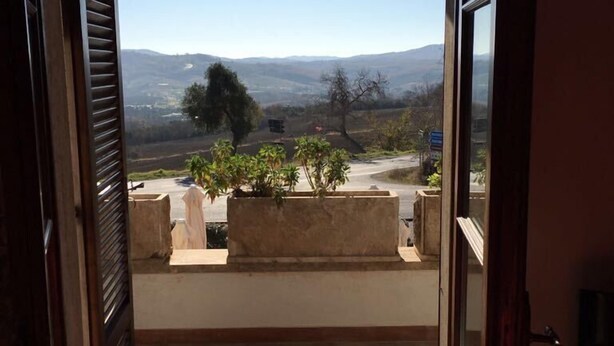 A doorway leading to a balcony with a view of a hilly landscape. - Affittacamere Villa Bagno Santo (Manciano)