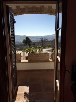 An open doorway leading to a balcony with a view of a road and distant hills. - Affittacamere Villa Bagno Santo (Manciano)