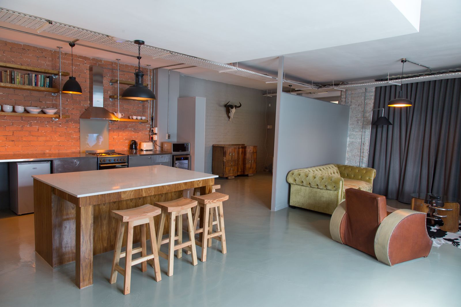 A modern kitchen with a large island, bar stools, and pendant lighting.
