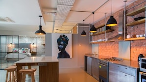 Une cuisine moderne dotée d’un îlot central, de tabourets de bar, de luminaires suspendus et d’un mur de briques en arrière-plan.