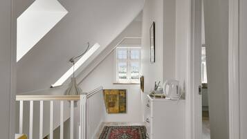 A staircase with a skylight, a patterned rug, and a painting on the wall.