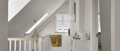 A staircase with a skylight, a patterned rug, and a painting on the wall.