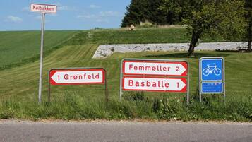 Directional signs for Gronfeld, Femmöller, and Basballe, and a bike route sign.