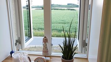 A room with a large window, a potted plant, a clock, and a small figurine.