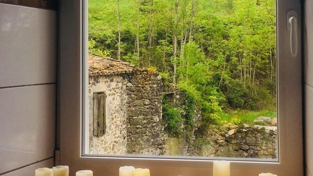Un baño con vista a un paisaje verde y un edificio de piedra.