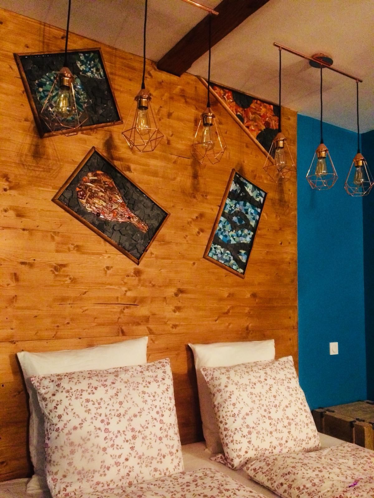 A bedroom with a wooden ceiling, a bed with floral pillows, and artwork on the wall.
