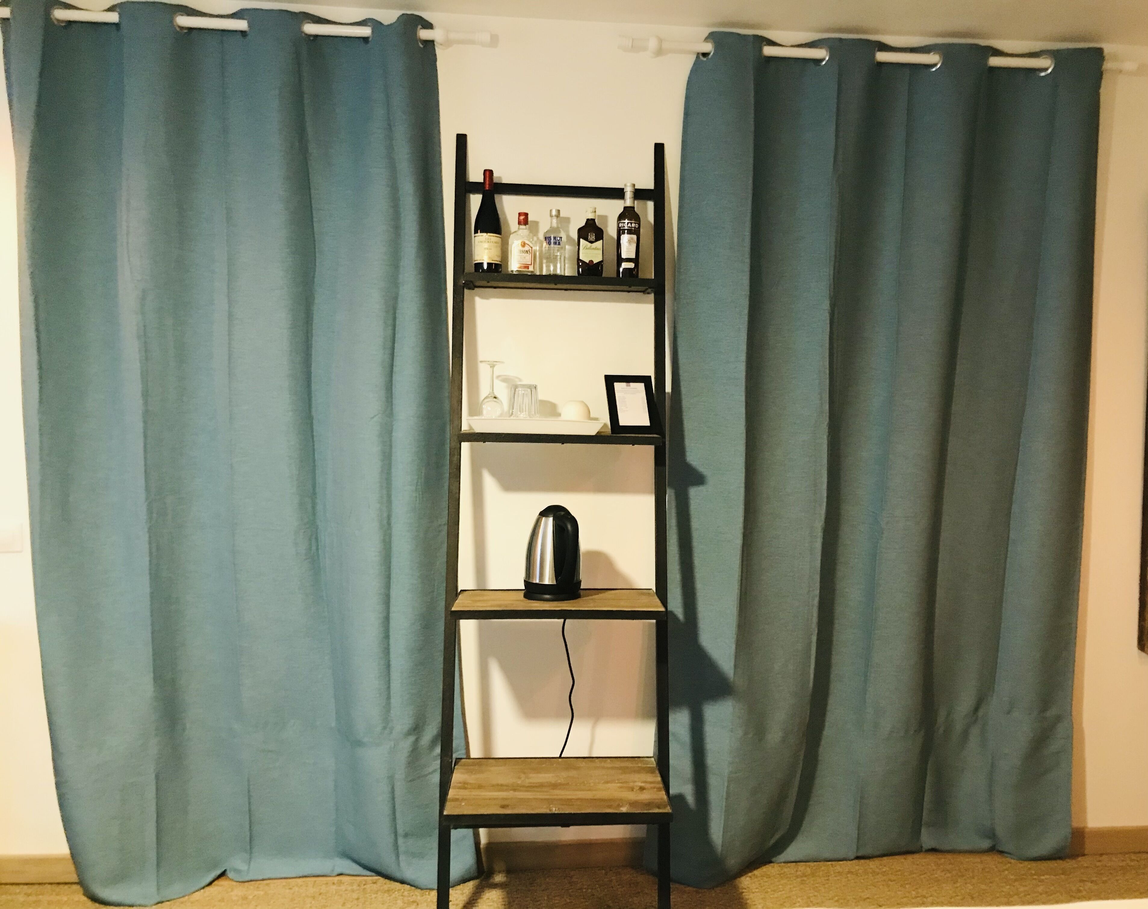 Ein Zimmer mit einer Holzhockerreih an der Wand, auf der verschiedene Flaschen und ein Wasserkocher stehen.