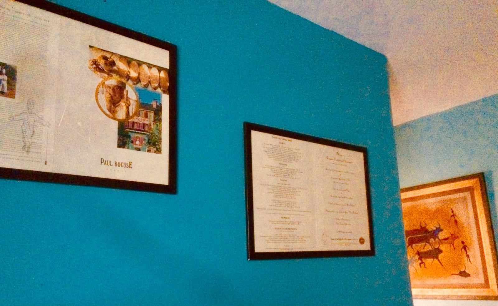Pared azul con tres documentos o certificados enmarcados.
