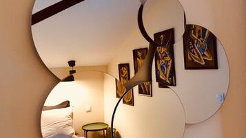 A circular mirror reflecting a bedroom with a bed, a nightstand, and wall art.