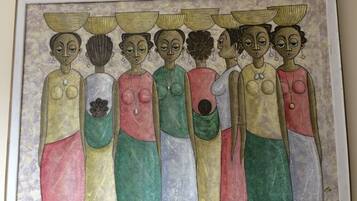 A framed artwork depicting a group of figures with baskets on their heads.