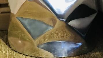 Un adorno de pared metálico y abstracto con formas geométricas frente a una pared de madera con tablones horizontales.