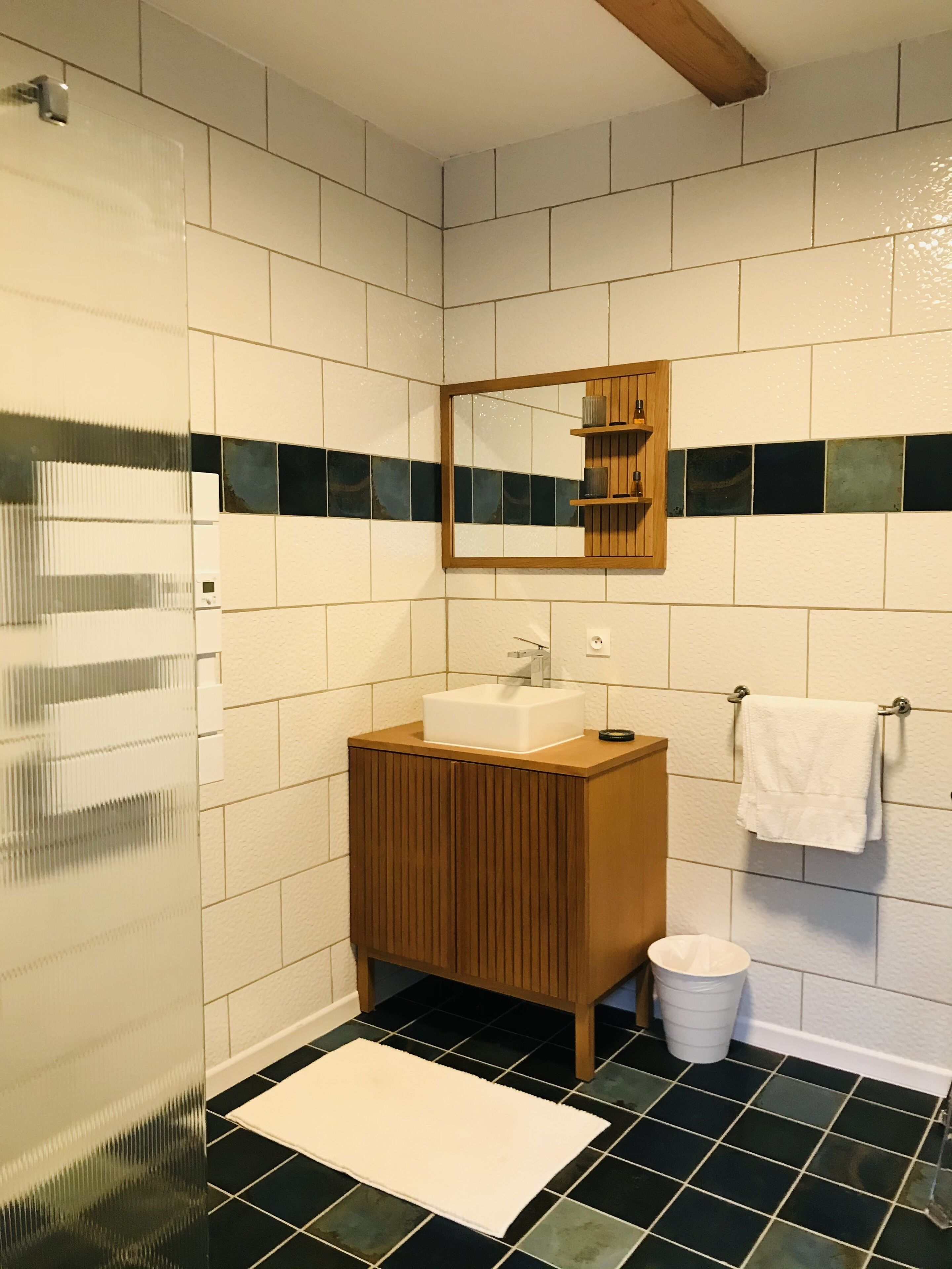 A bathroom with a white sink, wooden vanity, a mirror, and a tiled floor.