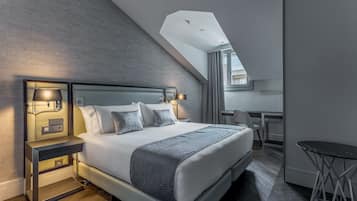 A modern hotel room with a large bed, bedside lamps, a desk, and a small table.