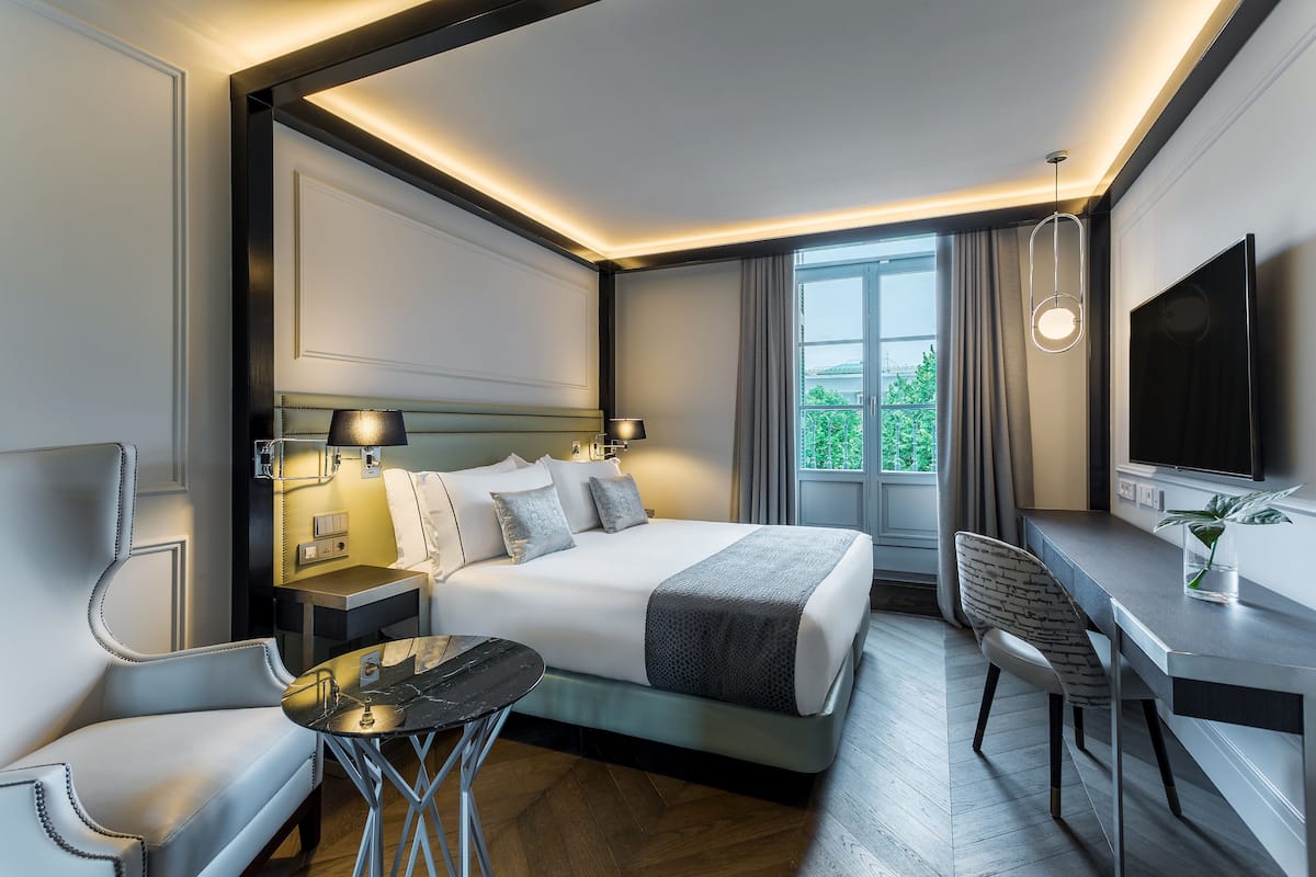 Una habitación de hotel moderna con una cama grande, un escritorio, una silla y un televisor.