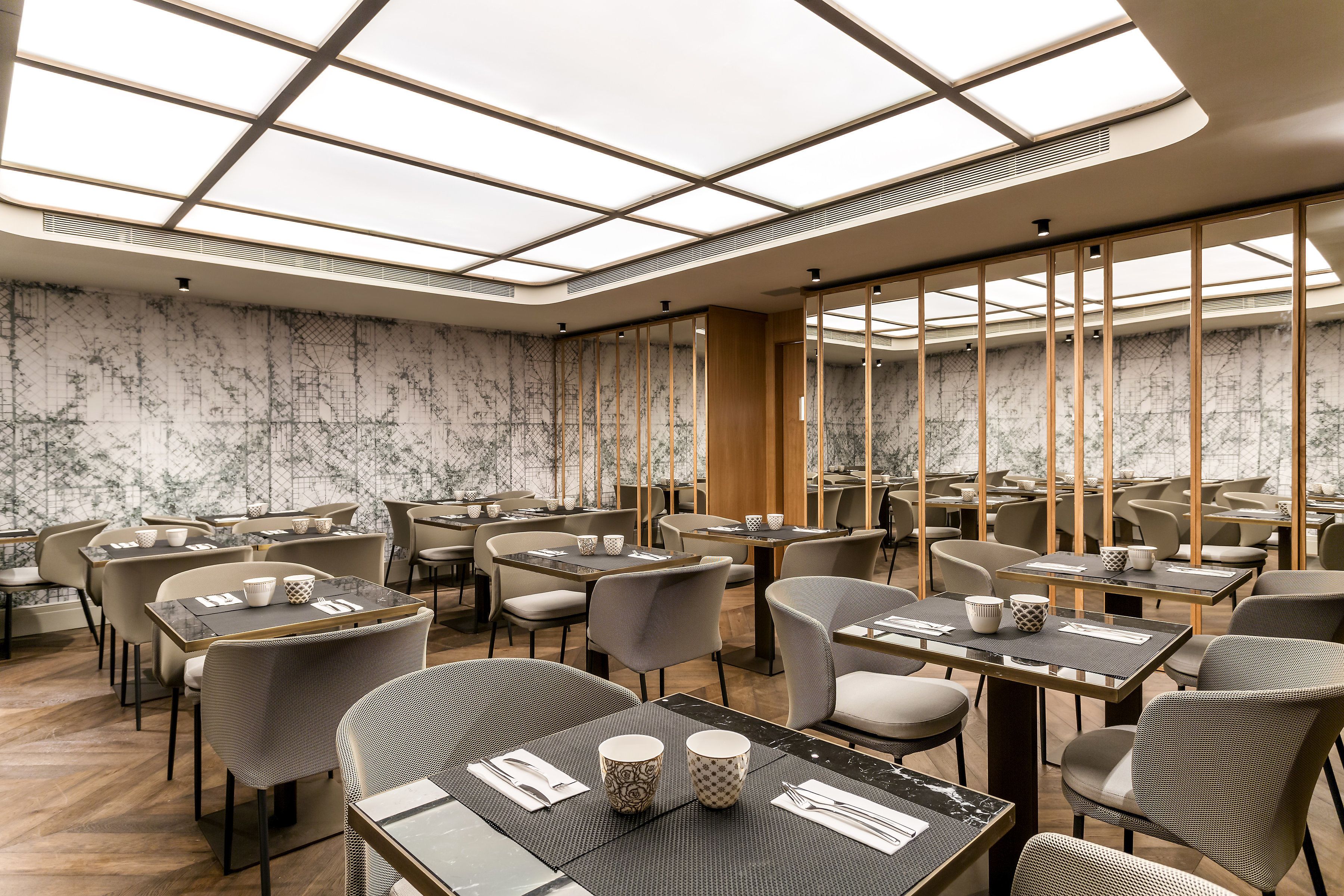 Un restaurant moderne doté d’un plafond haut, de murs en marbre et de différents types de sièges, notamment des tables et des chaises.