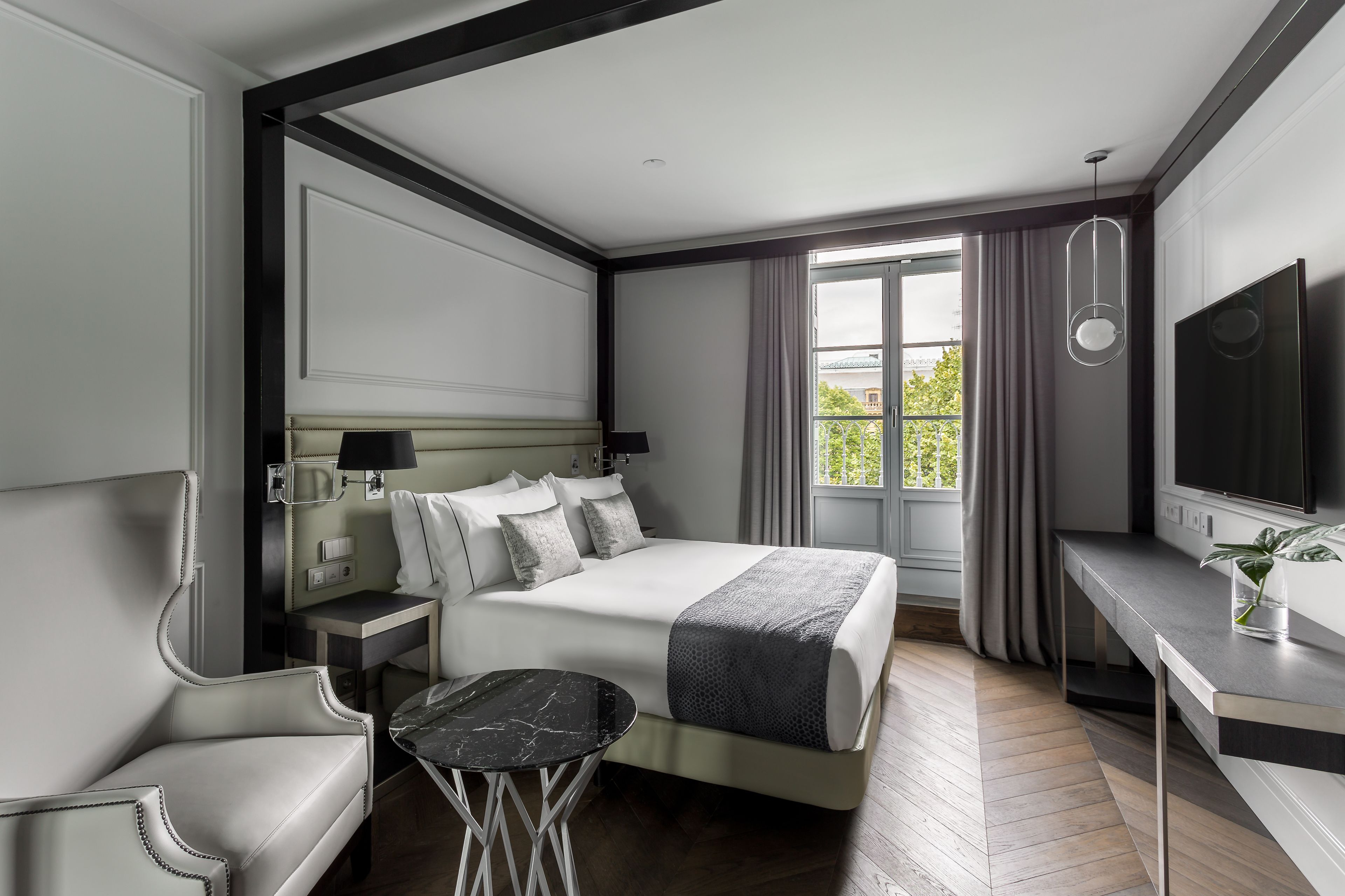 Una habitación de hotel moderna con una cama grande, un escritorio, una silla y un televisor.