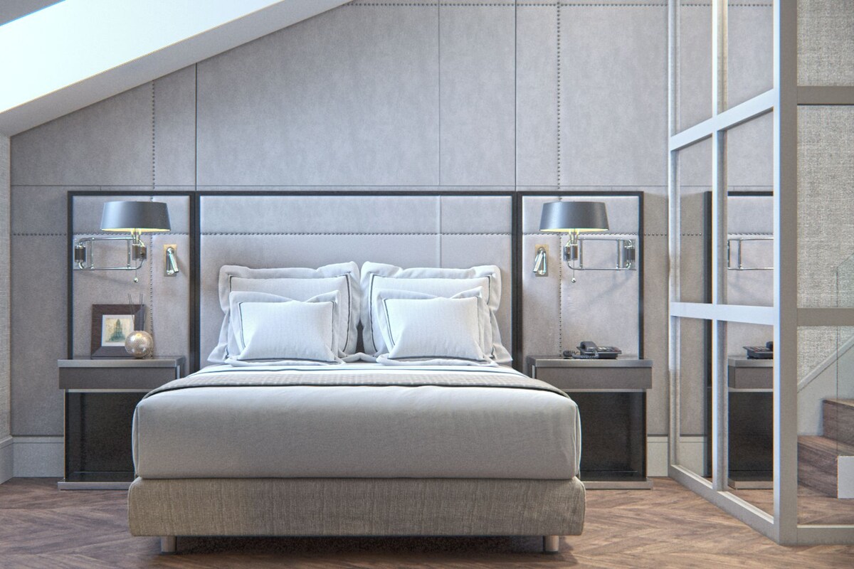 Un dormitorio moderno con una cama grande, dos mesitas de noche, una mesilla auxiliar, una lámpara de pared y un ventanal amplio.