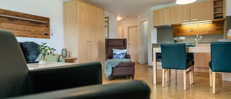 Una sala de estar moderna con un sofá, un sillón y un comedor con una mesa y sillas.