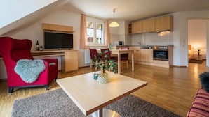 Een modern appartement met een eethoek, keuken en een rode fauteuil met een hartvormige plaid.