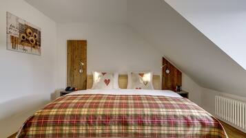 A bedroom with a large bed, wooden headboard, and a sloped ceiling.