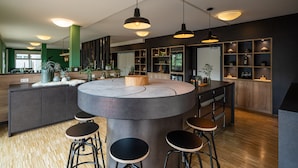 Een moderne keuken met een centraal eiland, barkrukken, hanglampen en houten schapjes.