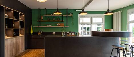 Una cocina moderna con armarios de madera, una isla central, iluminación colgante y vistas al exterior.
