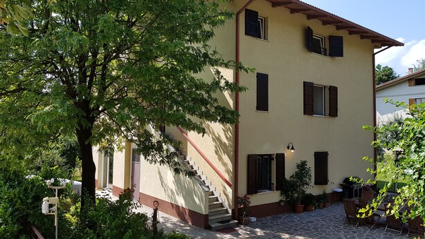 A two-story building with a staircase leading to the entrance, surrounded by greenery and potted plants. - Cherry House B&B (Polinago)